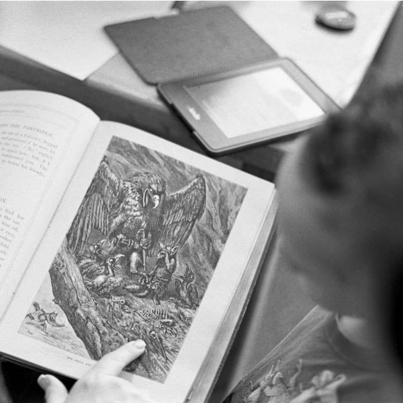 two people looking at an open book with a mythological illustration